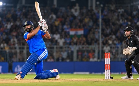 Illustration of an India batter in blue hitting a big shot as a New Zealand wicketkeeper watches at a floodlit ground